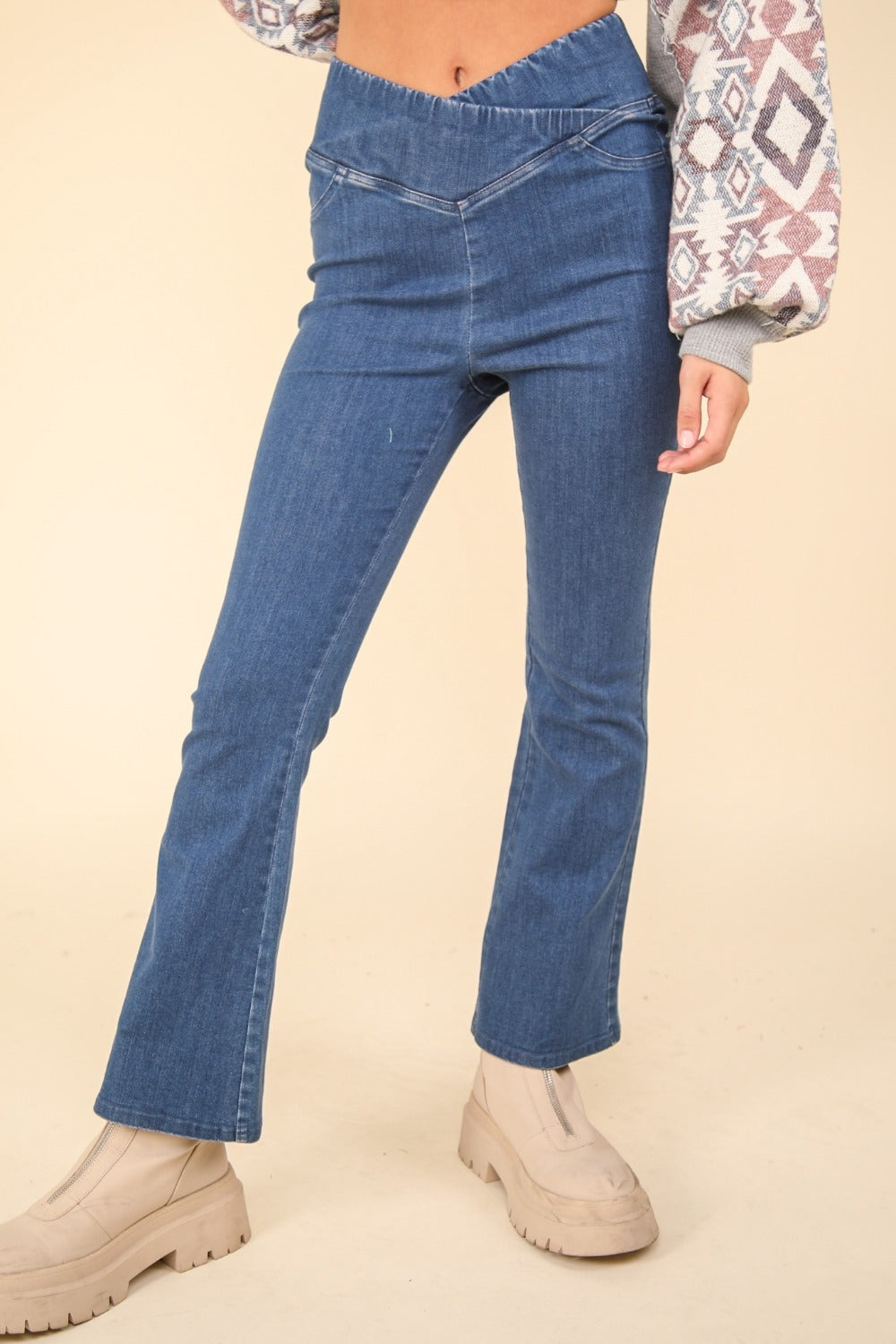 Person wearing VERY J Washed Denim Stretchy Crossover Waist Leggings with a hint of flared leg, and beige ankle-length boots. Only the lower half of the body is visible.