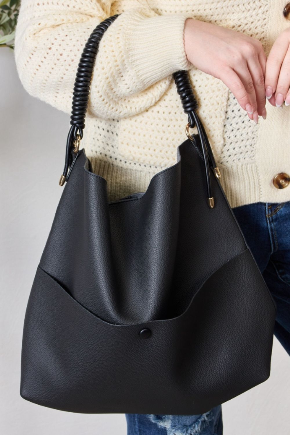 Person carrying a SHOMICO Vegan Leather Handbag with a front pocket and coiled handles, showcasing both versatility and durability.