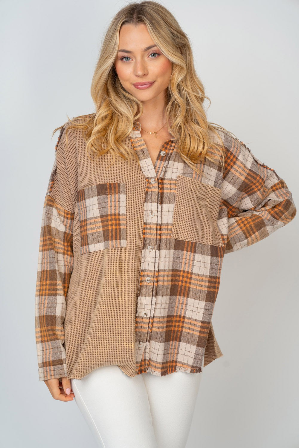A person with long, blonde hair smiles while wearing the White Birch Full Size Contrast Plaid Button Down Shirt in beige, brown, and white hues, paired with white pants.