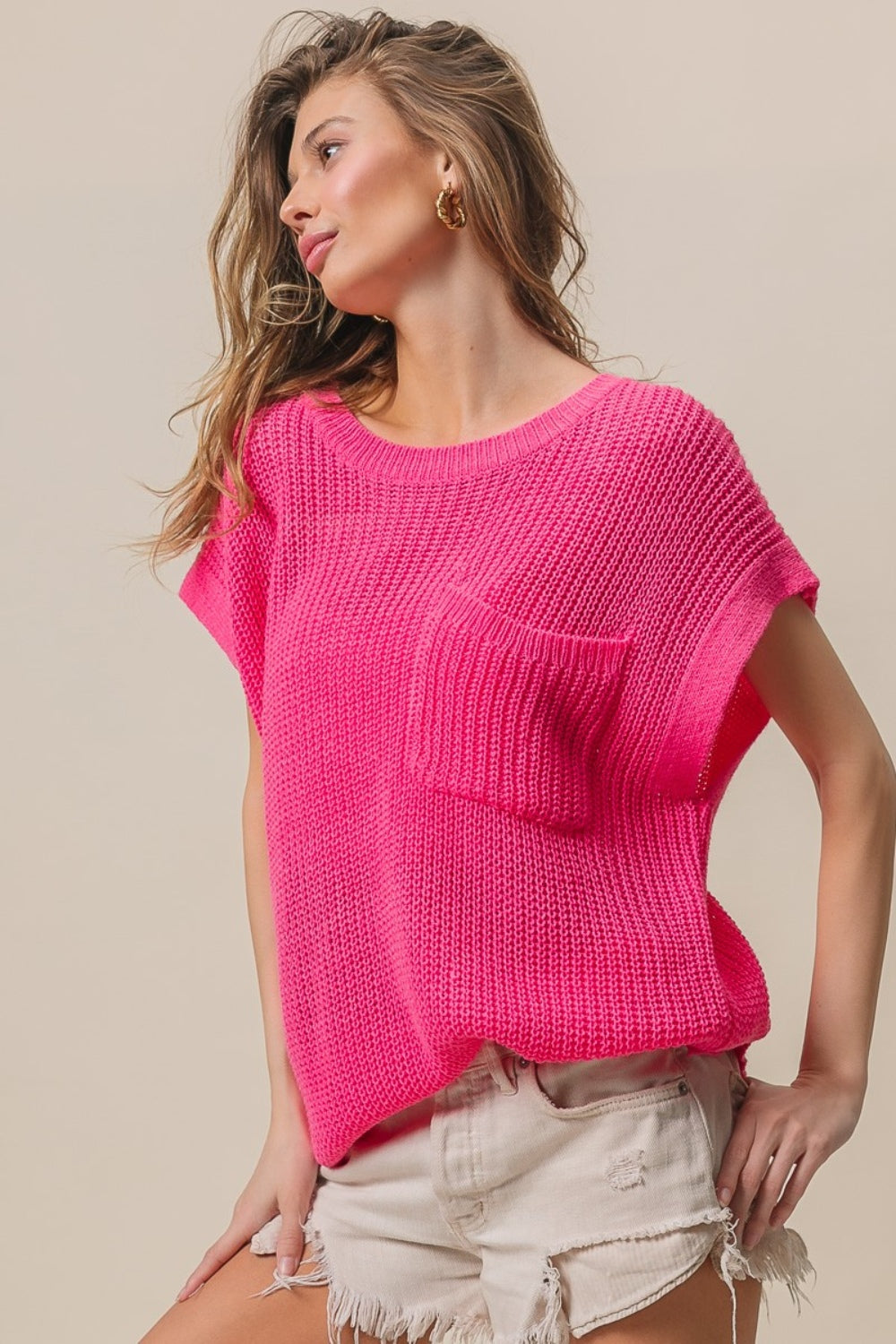 A woman wearing the BiBi Patch Pocket Short Sleeve Sweater, a cozy knit in pink.