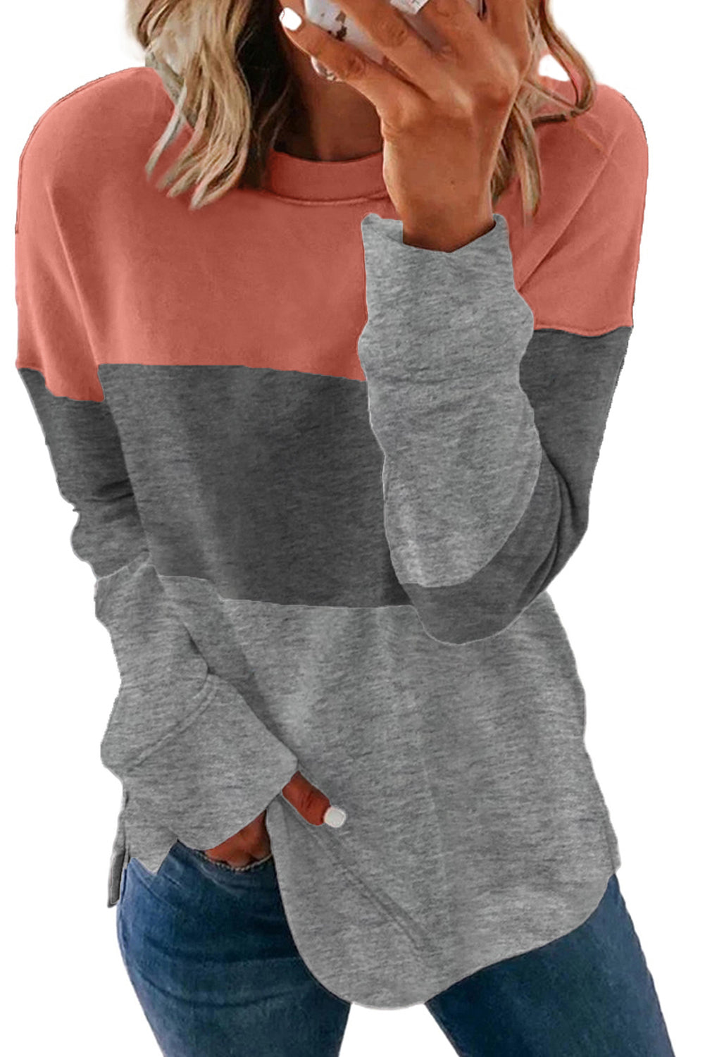 A Colorblock Gray Contrast Stitching Sweatshirt with Slits, made of comfy fabric and featuring coral, gray, and light gray sections, is placed on a wooden surface near sunglasses, a book, and some plant leaves.