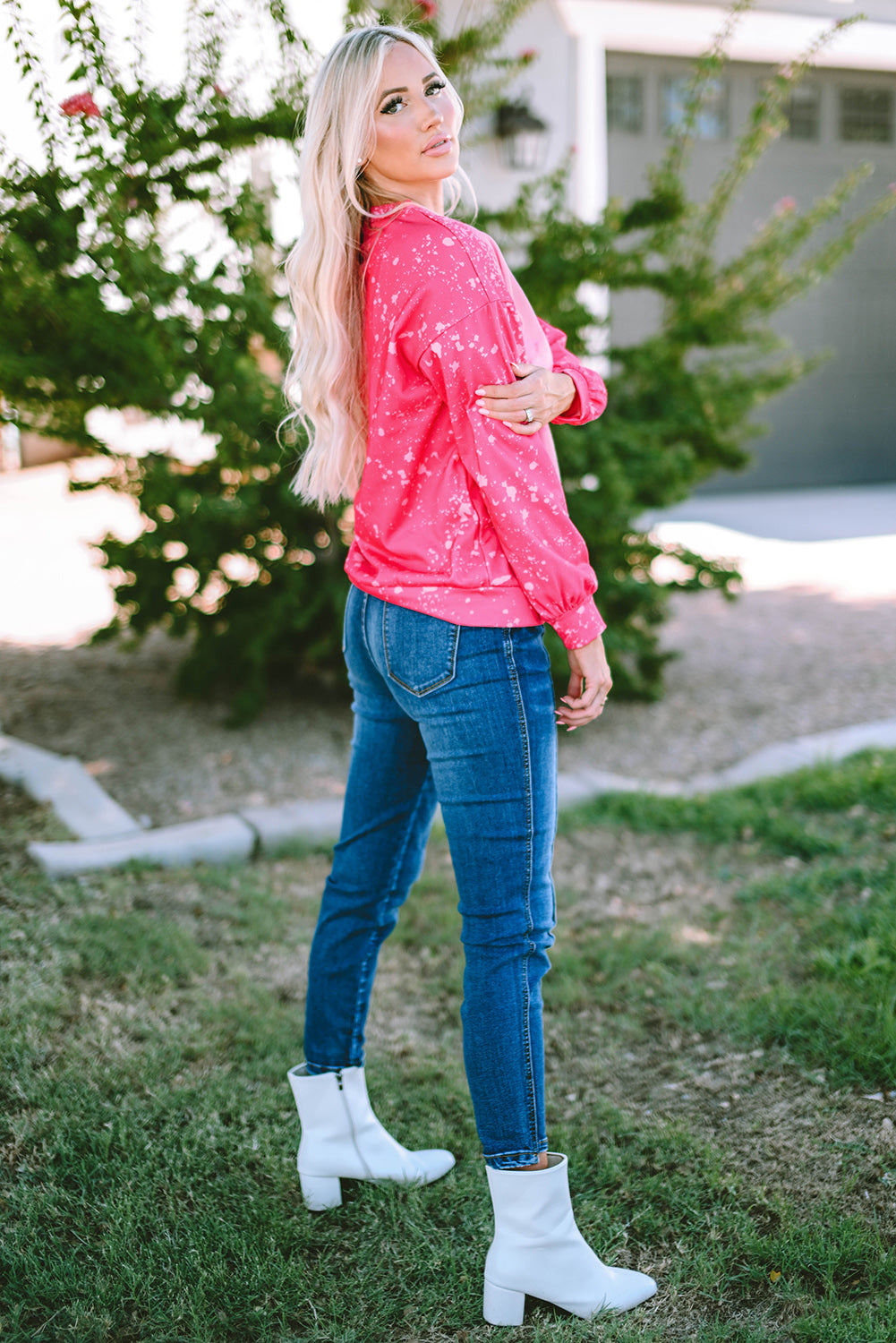 Person with long blonde hair wearing a Rose Tie Dye Long Sleeve Pullover Sweatshirt and blue jeans, standing outdoors with back to the camera.