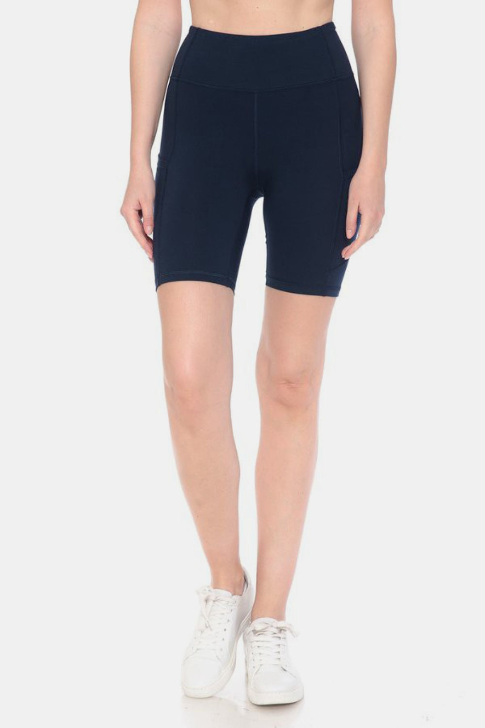 Person wearing Leggings Depot Full Size High Waist Active Shorts in black, made from moisture-wicking fabric, paired with white sneakers, standing upright against a neutral background.