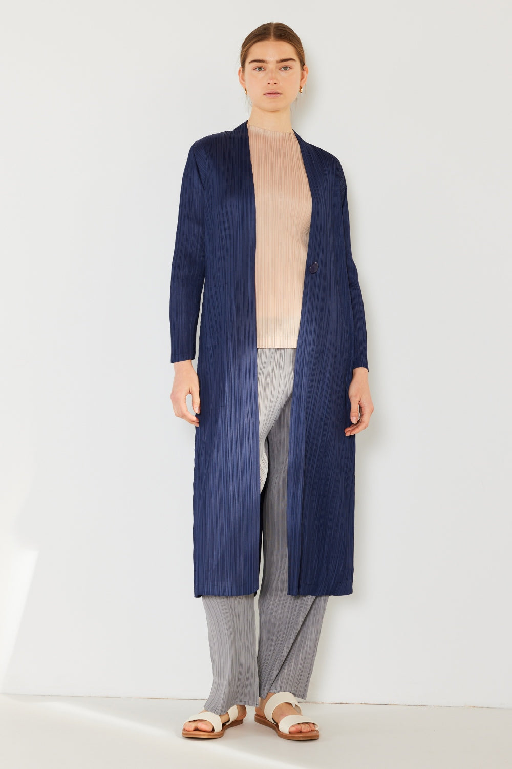 A person wears the Marina West Swim Pleated Long Sleeve Cardigan over a matching top and gray wide-leg pants, standing against a plain light background. This versatile layering piece, with its chic pleated long sleeves, adds an elegant touch to the ensemble.