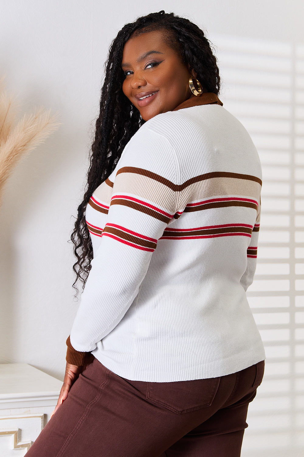 A person wearing the Basic Bae Striped Collared Neck Rib-Knit Top and dark pants is smiling and standing indoors against a light background.