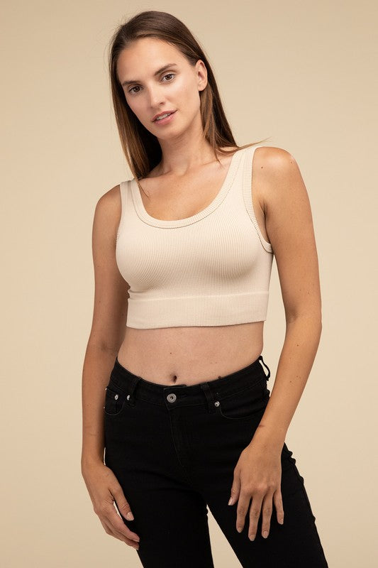 A person with long brown hair wearing the Ribbed Seamless Crop Top in light blue and black pants stands against a beige background, showcasing a perfect summer essential.