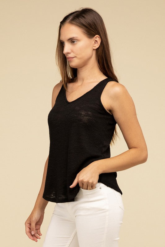 A woman in a stylish and adaptable V Neck Sleeveless Cami Top paired with jeans stands against a beige background. She has long brown hair and maintains a neutral expression.