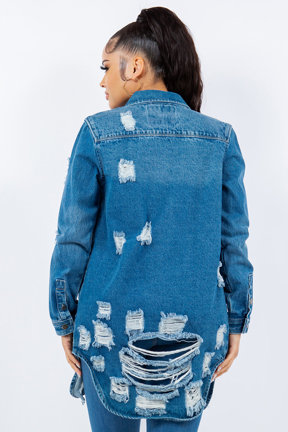 Woman wearing an American Bazi Distressed Button Up Long Sleeve Denim Jacket over a white crop top and blue jeans, standing against a plain background.