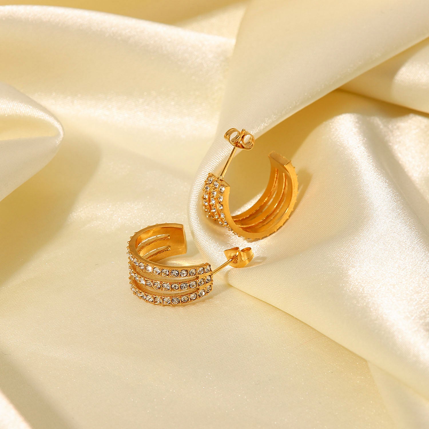 The Stainless Steel Inlaid Zircon C-Hoop Earrings perfectly blend elegance, featuring a triple row of small, clear gemstones on each gold-plated hoop.