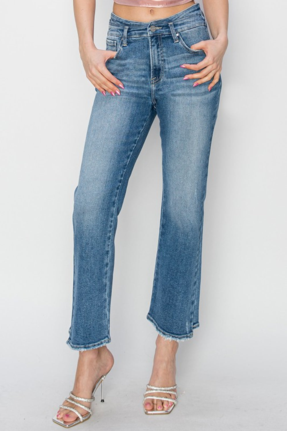 A person wearing RISEN High Rise Slim Straight Jeans with frayed hems and open-toe high-heeled sandals adorned with pearl details, standing against a plain white background.