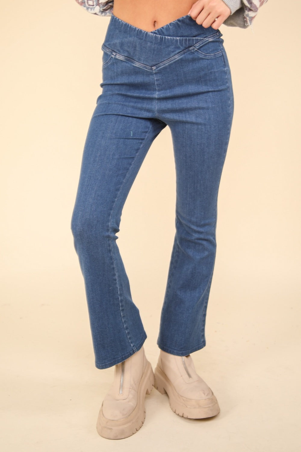 Person wearing VERY J Washed Denim Stretchy Crossover Waist Leggings with a hint of flared leg, and beige ankle-length boots. Only the lower half of the body is visible.