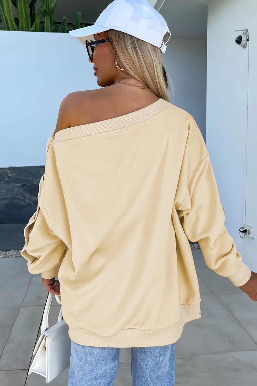 Woman with long wavy hair wearing the Beige Buttoned Sleeve Dropped Shoulder Sweatshirt, standing in a bright indoor setting.