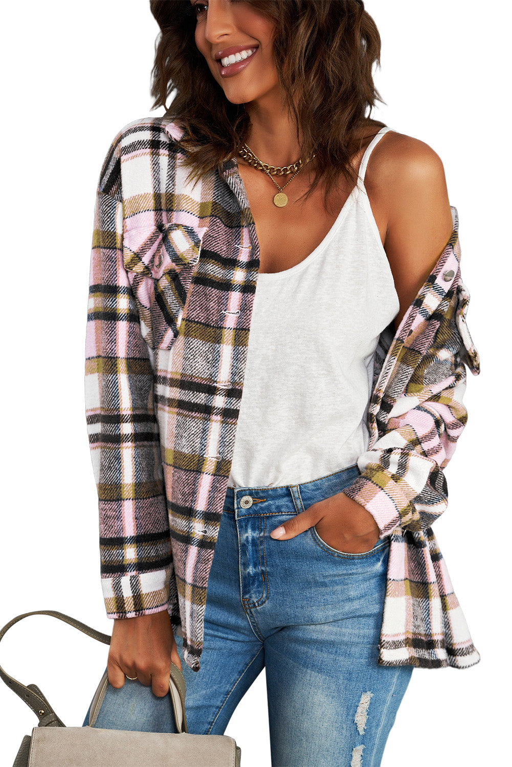 A person wearing a Brown Plaid Button Up Long Sleeve Flannel Shacket layered over a white top with ripped jeans and holding a brown handbag stands against a textured gray wall.