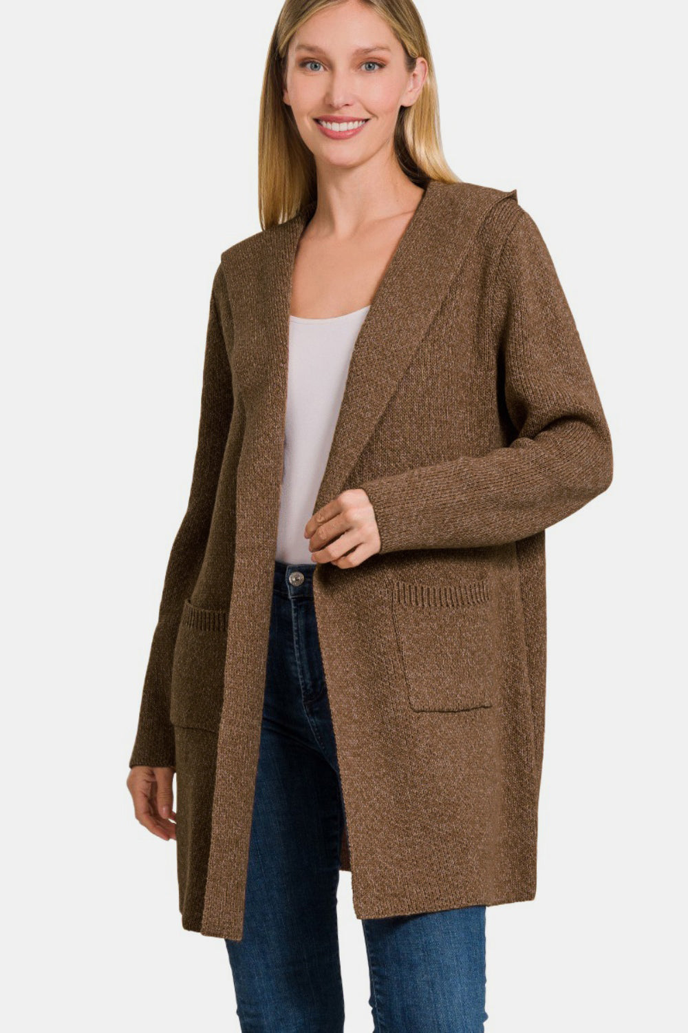 A person wearing a cozy layering piece—a Zenana Hooded Open Front Sweater Cardigan in brown over a white top and jeans—stands against a plain background.