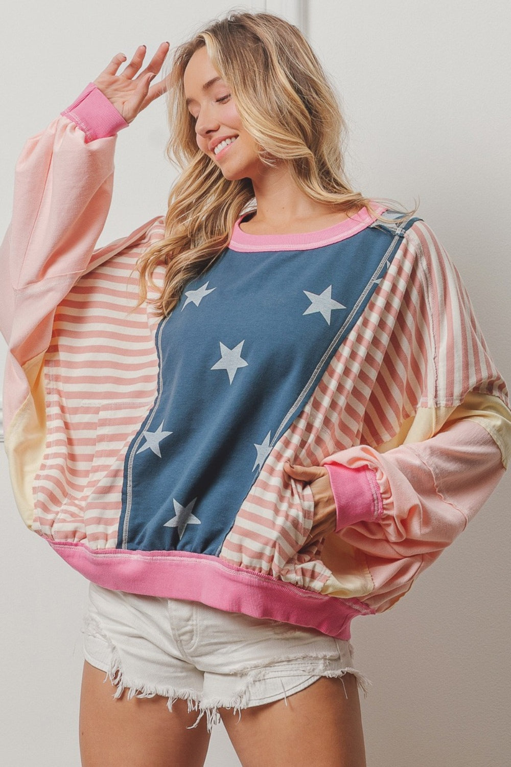 A woman wearing a BiBi Stars and Stripes Round Neck Long Sleeve Top paired with white shorts, standing against a plain background.