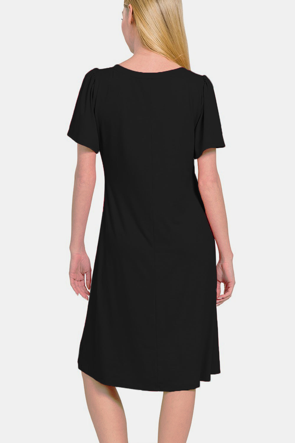 A woman with straight blonde hair, wearing a versatile and timeless Zenana V-Neck Short Sleeve, knee-length black dress.