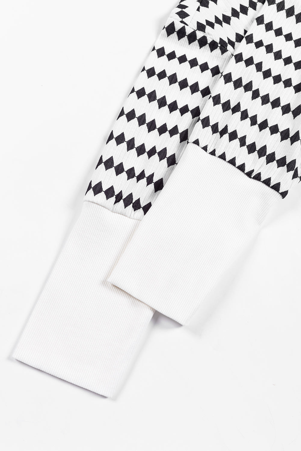 A woman in a Black Stripe Argyle Striped Half Button Oversized Hoodie stands in a room with light green brick walls, a painting of a sailboat, and a fan.