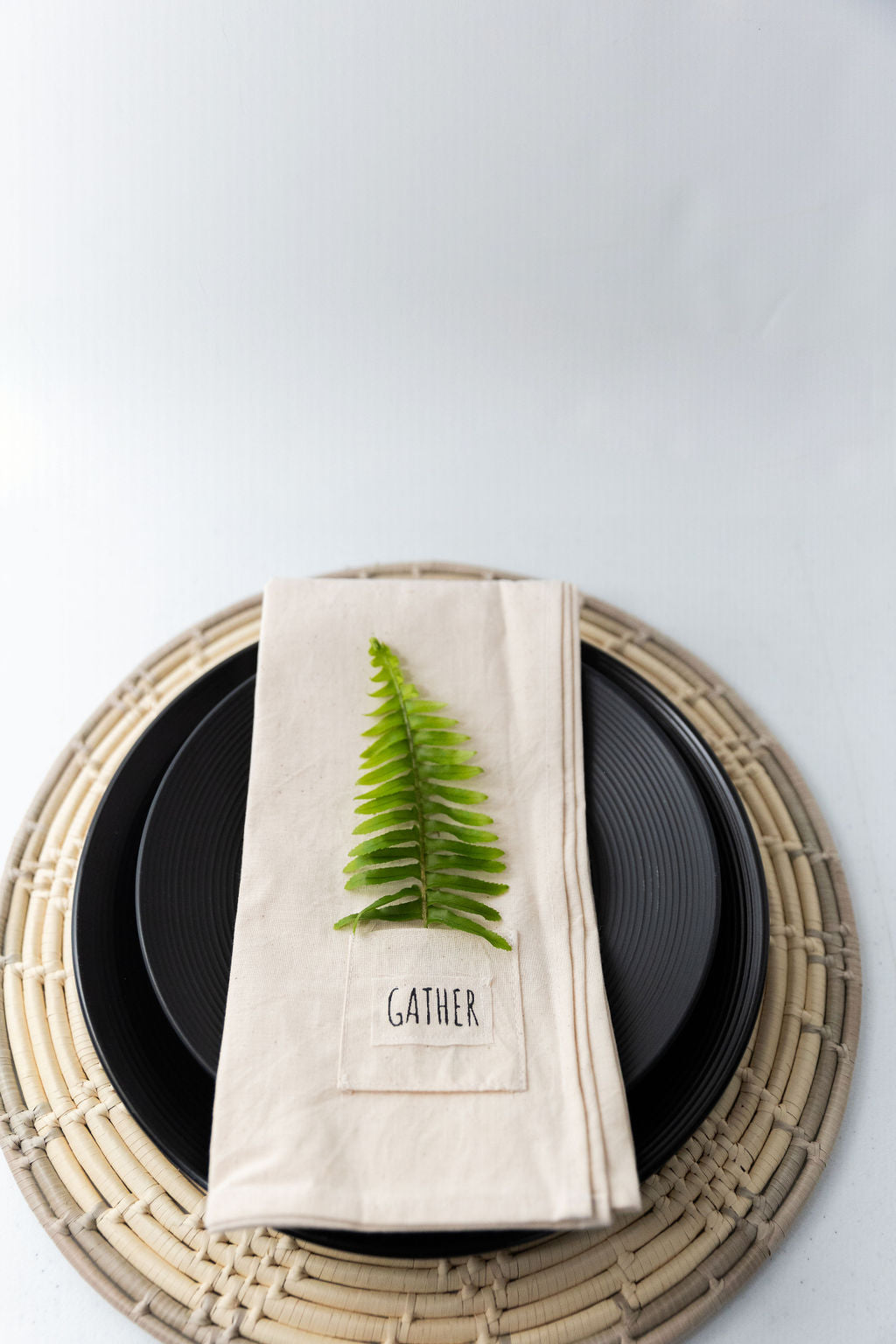 Pocket napkin set of four, skillfully crafted from up-cycled fabric, folded with a eucalyptus sprig and wooden ring, labeled "SAVOR.