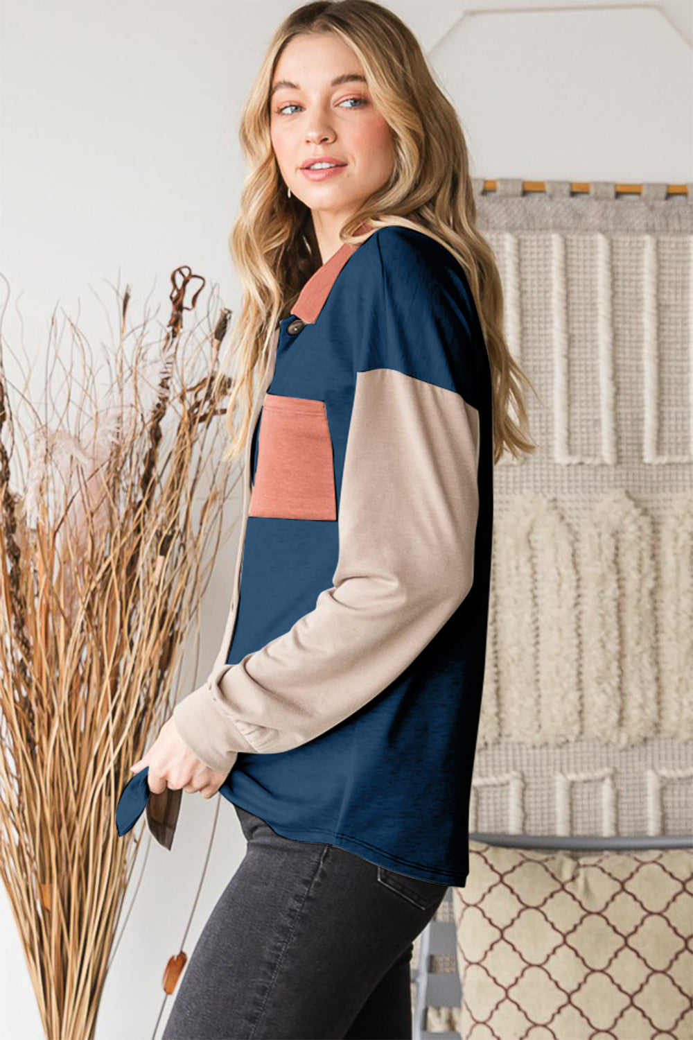 A woman stands indoors wearing the Heimish Full Size Color Block Button Down Shirt, set against a backdrop of a woven tapestry, highlighting her versatile wardrobe.