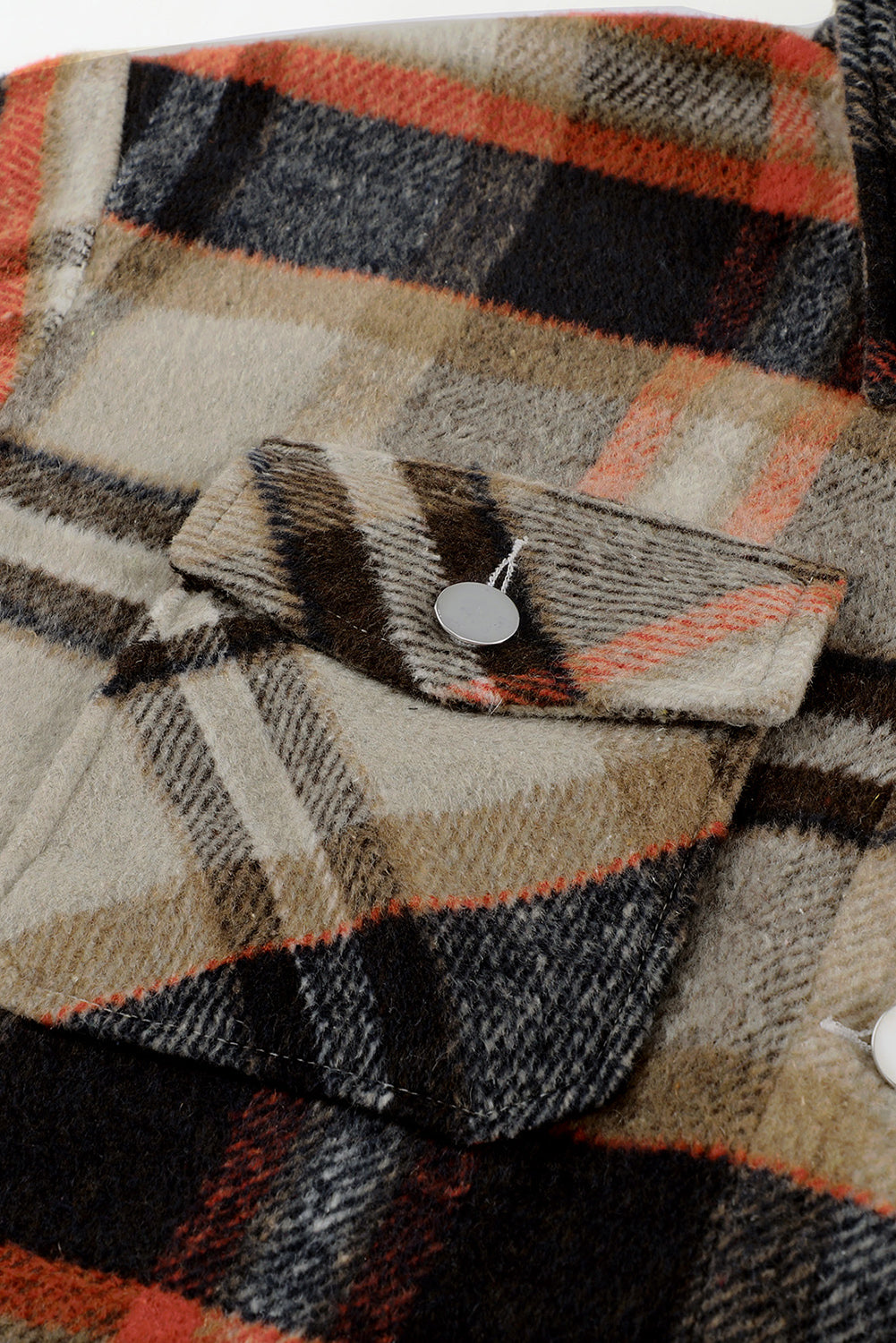 A person wearing a Brown Plaid Button Up Long Sleeve Flannel Shacket layered over a white top with ripped jeans and holding a brown handbag stands against a textured gray wall.