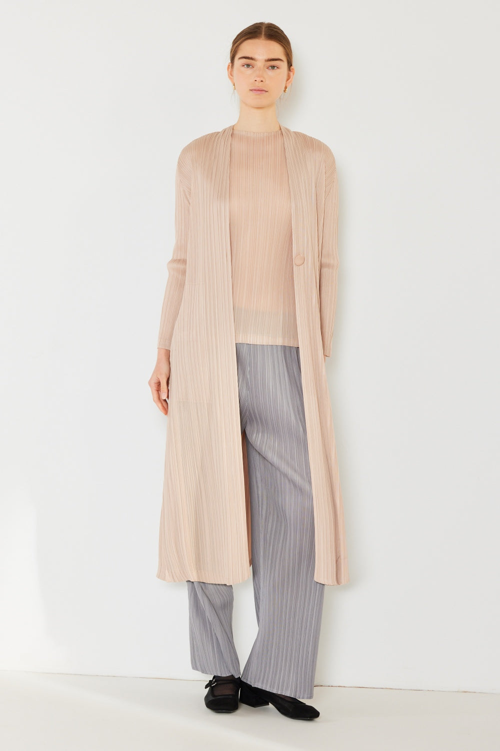 A person wears the Marina West Swim Pleated Long Sleeve Cardigan over a matching top and gray wide-leg pants, standing against a plain light background. This versatile layering piece, with its chic pleated long sleeves, adds an elegant touch to the ensemble.