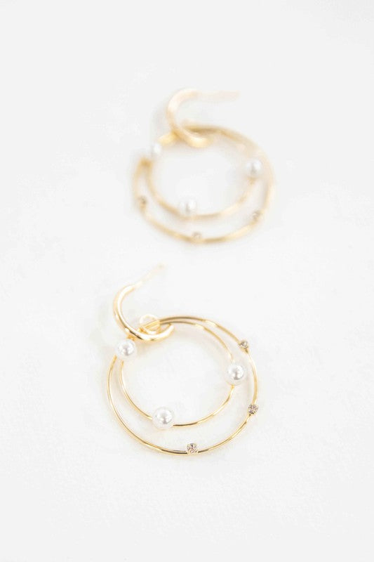 The Fawn Pearl Hoop Earrings, elegantly enhanced with pearls, gleam on a pristine white background, featuring lustrous 10k gold plating.