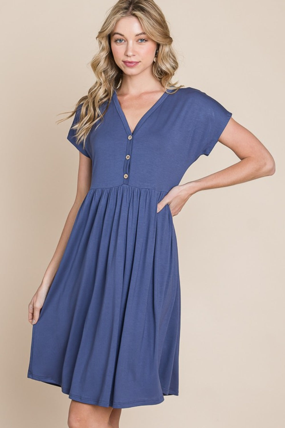 The BOMBOM V-Neck Short Sleeve Dress, crafted from soft rayon spandex fabric, showcases a blue hue with short sleeves and distinctive button accents.