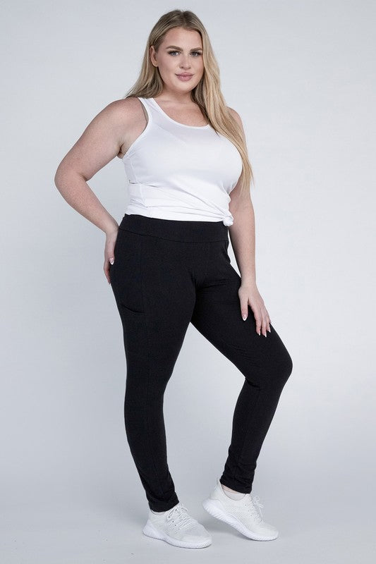 A person with long hair in casual attire is wearing a white t-shirt, Plus Everyday Leggings with Pockets in black, and white sneakers. They are holding a white cap and sporting a black crossbody bag.