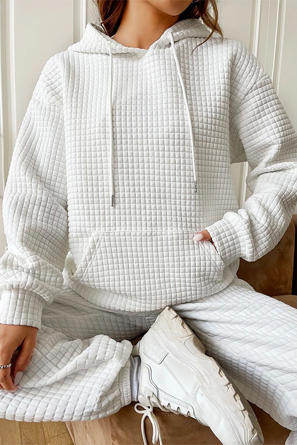 A person wearing a White Quilted Kangaroo Pocket Drawstring Hoodie and matching pants is standing with their back facing the camera.