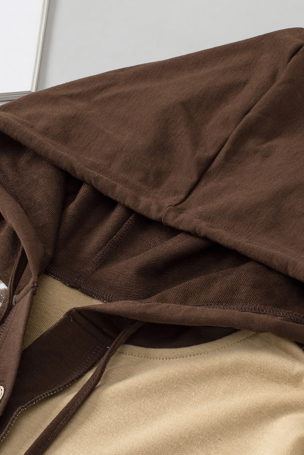 A person with long hair is seen from behind, wearing the Brown Leopard Print Colorblock Chest Pocket Henley Hoodie, which features a tan and brown casual look with stylish leopard print sleeves.