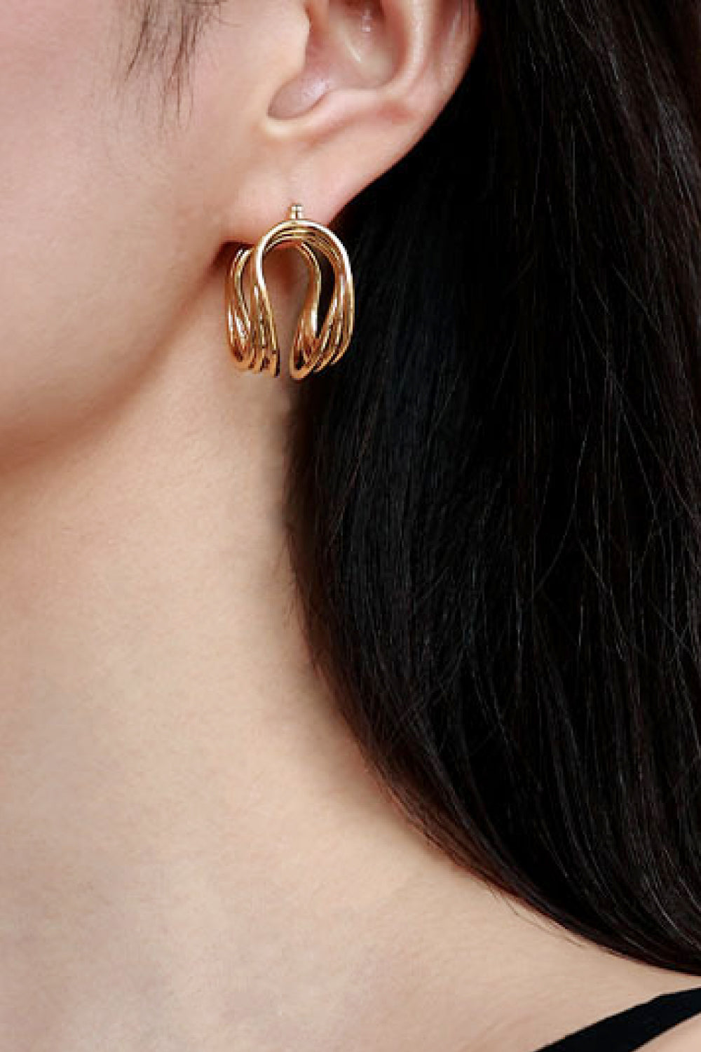 The U-Shaped Hoop Earrings feature a layered, wavy design on a light background, making them a stunning addition to any jewelry collection. These exquisite brass earrings showcase elegant craftsmanship, perfect for both casual and formal occasions.