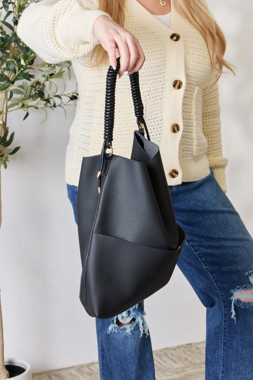 Person carrying a SHOMICO Vegan Leather Handbag with a front pocket and coiled handles, showcasing both versatility and durability.