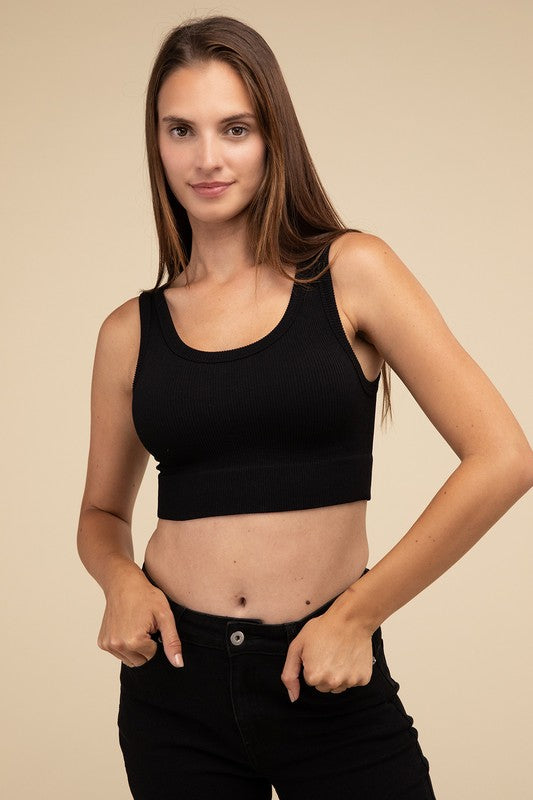 A person with long brown hair wearing the Ribbed Seamless Crop Top in light blue and black pants stands against a beige background, showcasing a perfect summer essential.