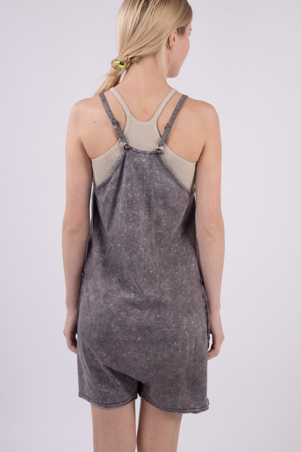 A person smiling against a plain background is wearing the VERY J V-Neck Sleeveless Washed Romper in gray, featuring two front pockets.