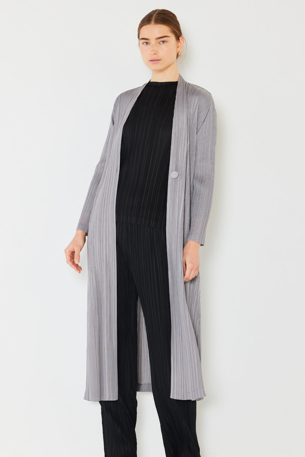 A person wears the Marina West Swim Pleated Long Sleeve Cardigan over a matching top and gray wide-leg pants, standing against a plain light background. This versatile layering piece, with its chic pleated long sleeves, adds an elegant touch to the ensemble.