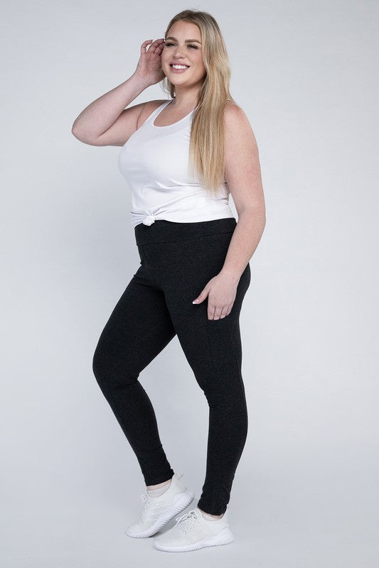 A person with long hair in casual attire is wearing a white t-shirt, Plus Everyday Leggings with Pockets in black, and white sneakers. They are holding a white cap and sporting a black crossbody bag.