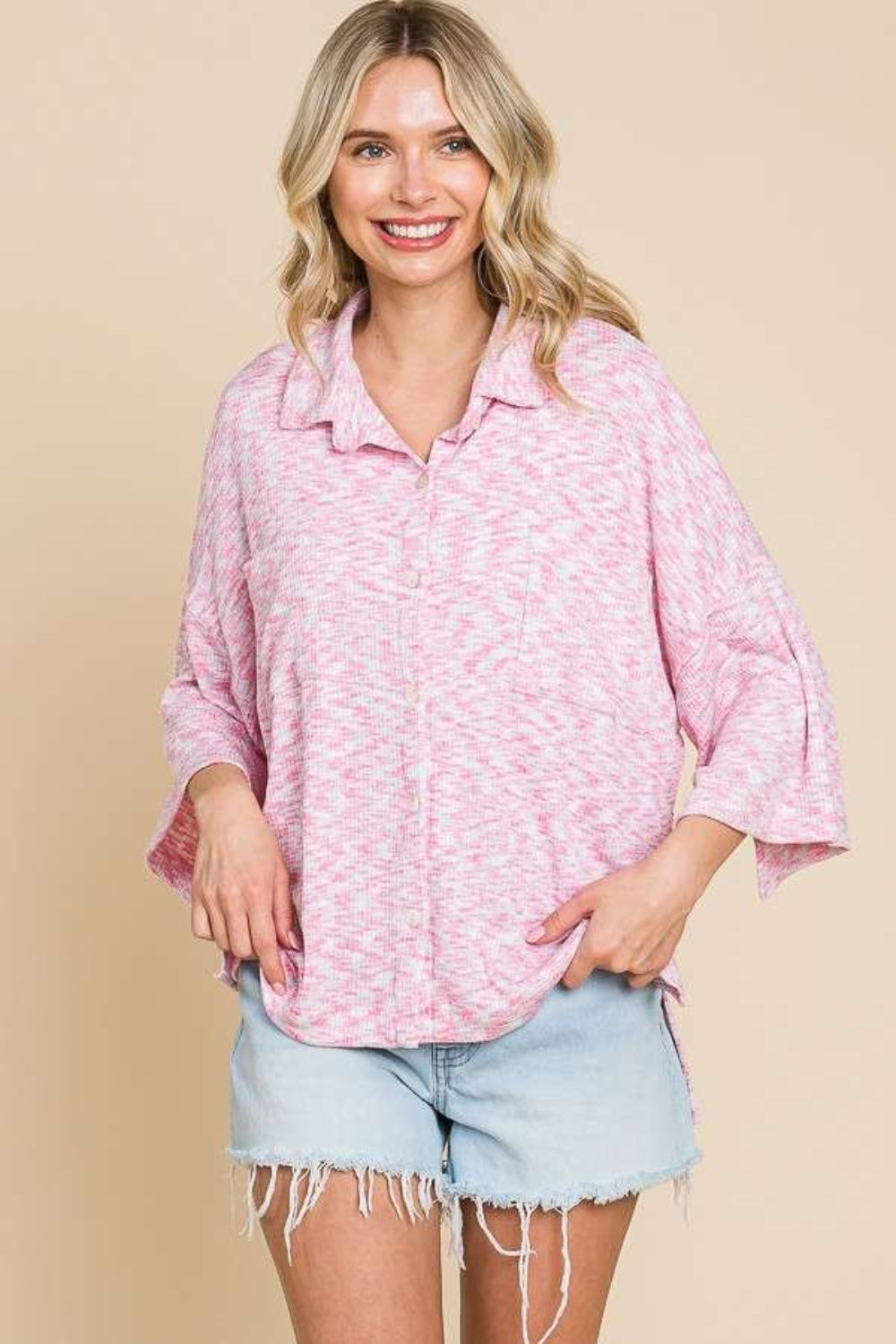 A person wearing the Culture Code Button Up Drop Shoulder Slit Shirt in pink, along with a white crop top, denim shorts, and a red cap, smiles against a neutral background.