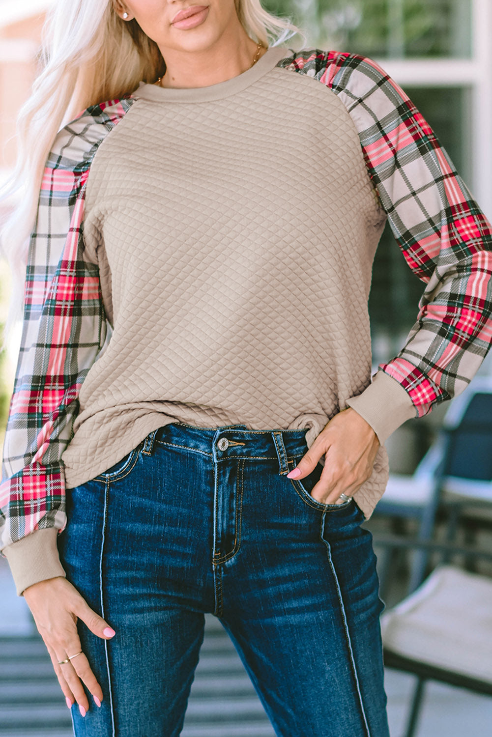 A person with long blonde hair stands with their back to the camera, wearing an Apricot Plaid Raglan Sleeve Sweatshirt and blue jeans.