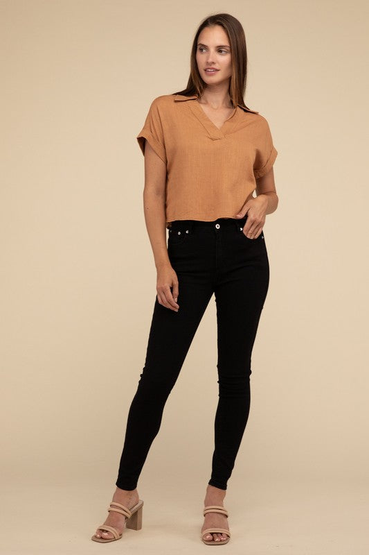 A woman with long hair is wearing the Always a Delight Short Sleeve Linen Top in brown and black pants, standing against a beige background.