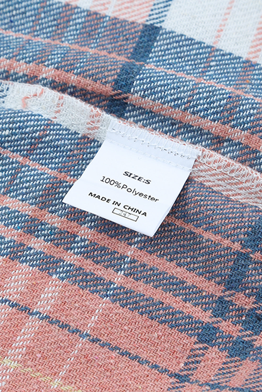 A woman wearing a white top, blue jeans, and the Gold Flame & Grey Plaid Button Up Collared Flannel Shacket smiles while posed outdoors.