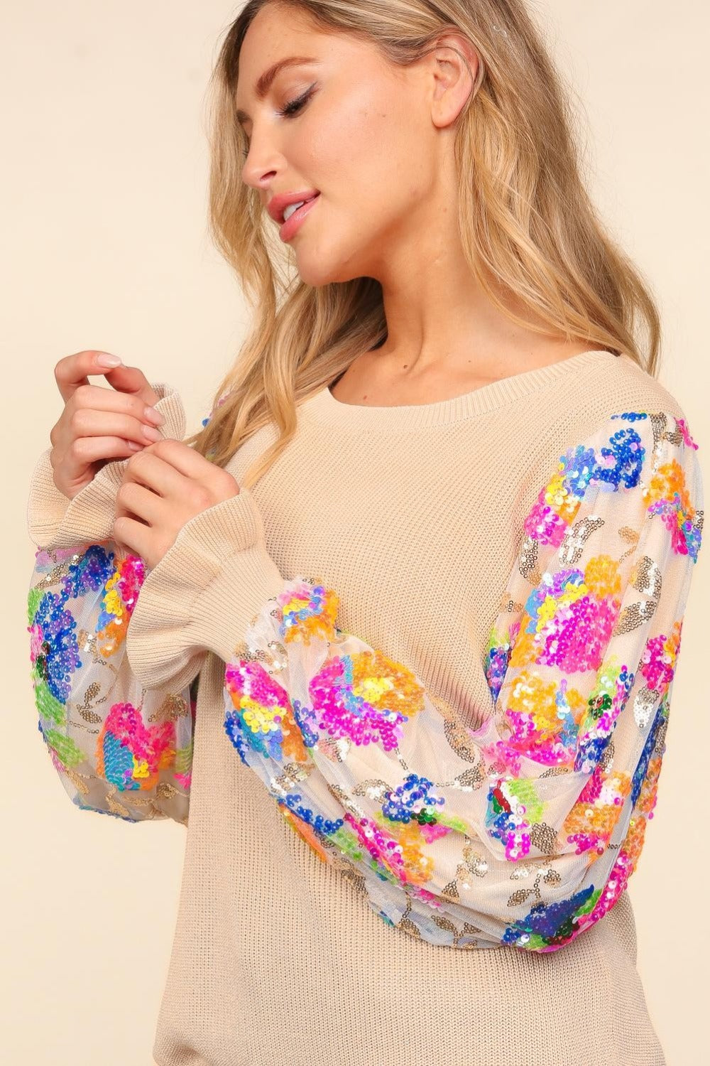 A person wearing the Haptics Floral Sequins Mesh Flounce Sleeve Sweater and blue jeans poses against a plain background.