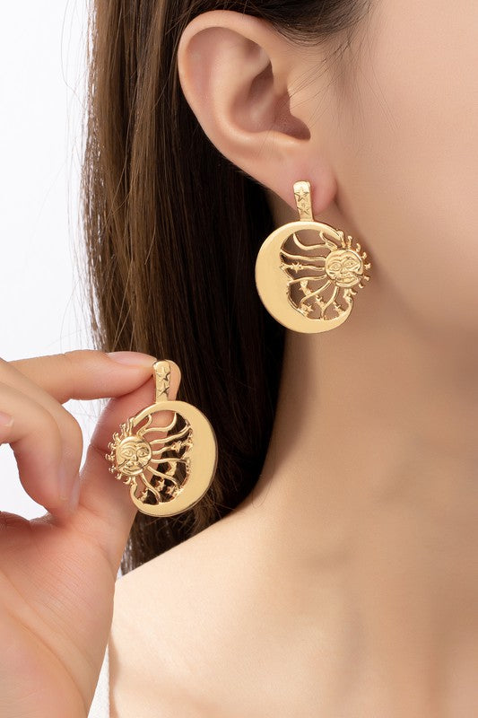 A close-up shows a person wearing the Sun Inside a Crescent Hoop Drop Earrings in large, gold-toned style, highlighting the intricate design with their hand.