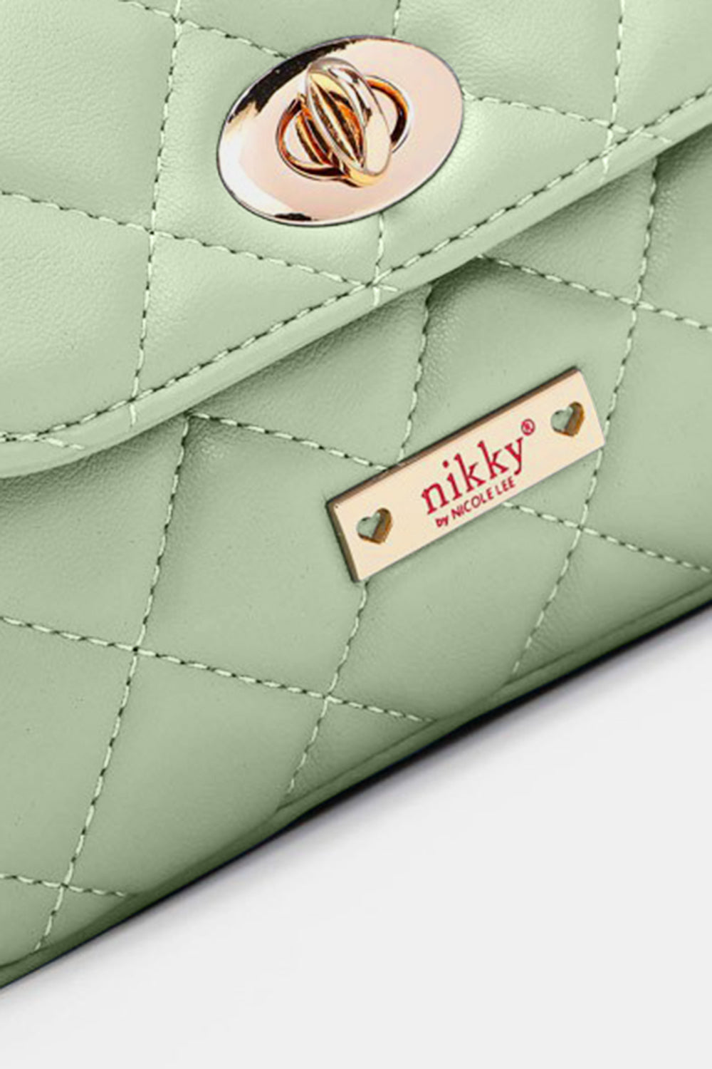 The Nicole Lee USA Quilted Fanny Pack is a light green, quilted crossbody bag crafted from vegan leather. It features gold hardware, including a twist-lock closure and a chain strap interwoven with orange leather accents. The brand name is visible on a gold plate at the front.