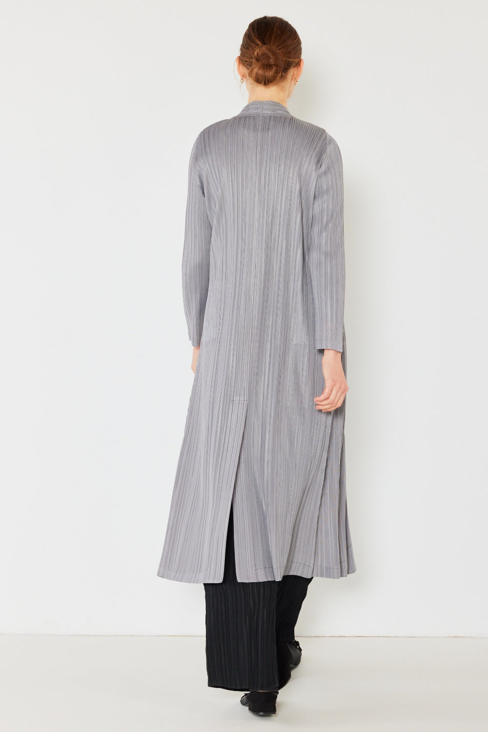 A person wears the Marina West Swim Pleated Long Sleeve Cardigan over a matching top and gray wide-leg pants, standing against a plain light background. This versatile layering piece, with its chic pleated long sleeves, adds an elegant touch to the ensemble.