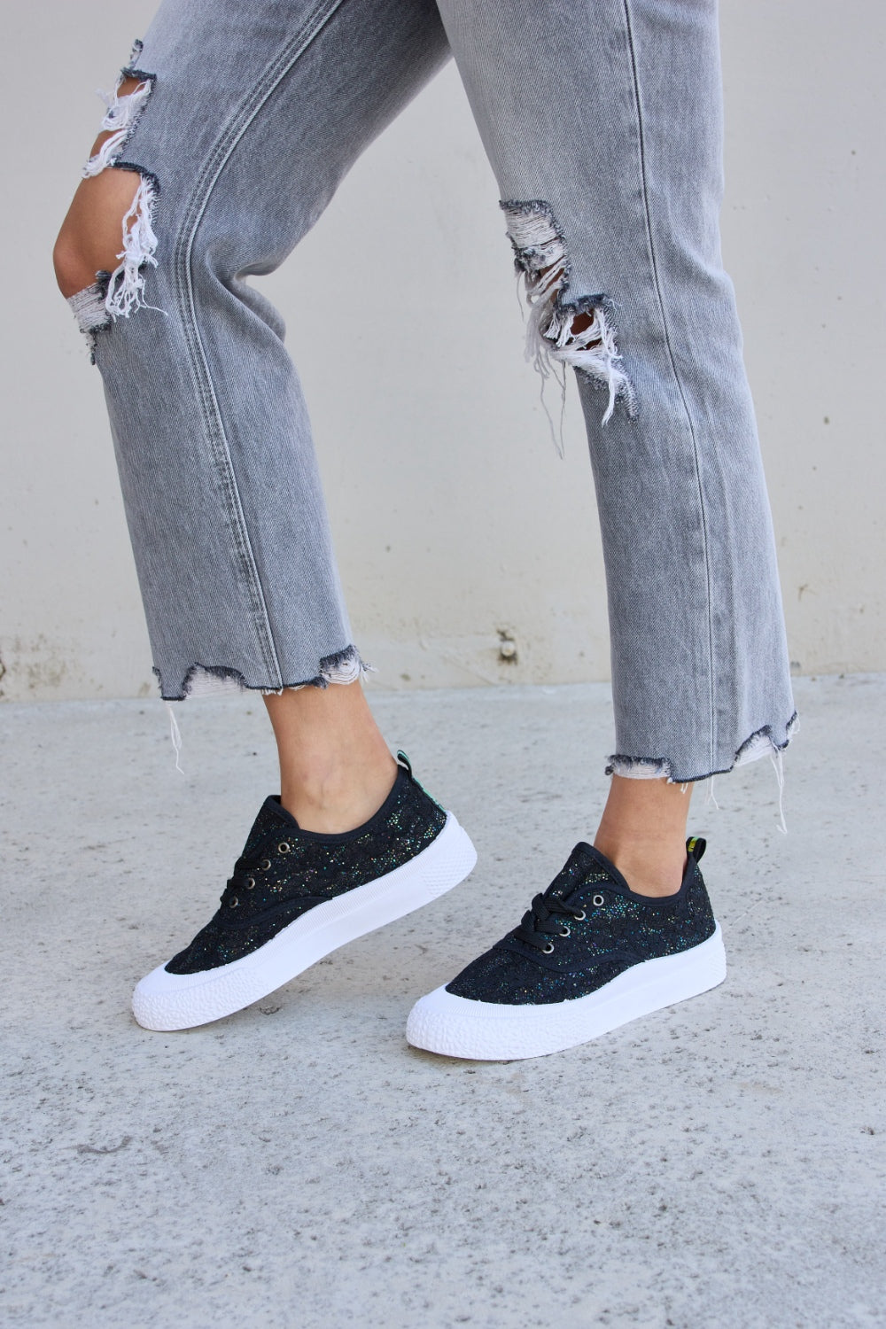 Person wearing ripped gray jeans and Forever Link Sequin Lace-Up Platform Sneakers.