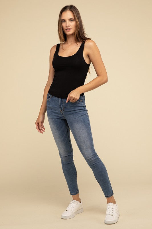 Dressed in a Double Layer Round Neck Tank Top and jeans, the person exudes stylish comfort while standing against a beige background.