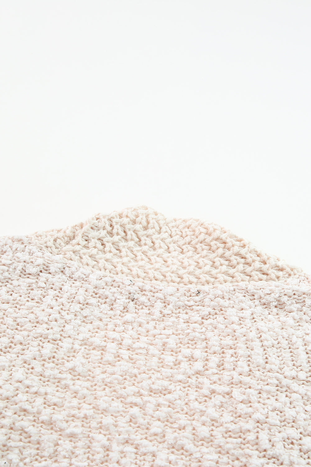 A woman in an Apricot Popcorn Knit Open Front Cardigan and jeans stands against a brick wall, looking to the side with a slight smile.