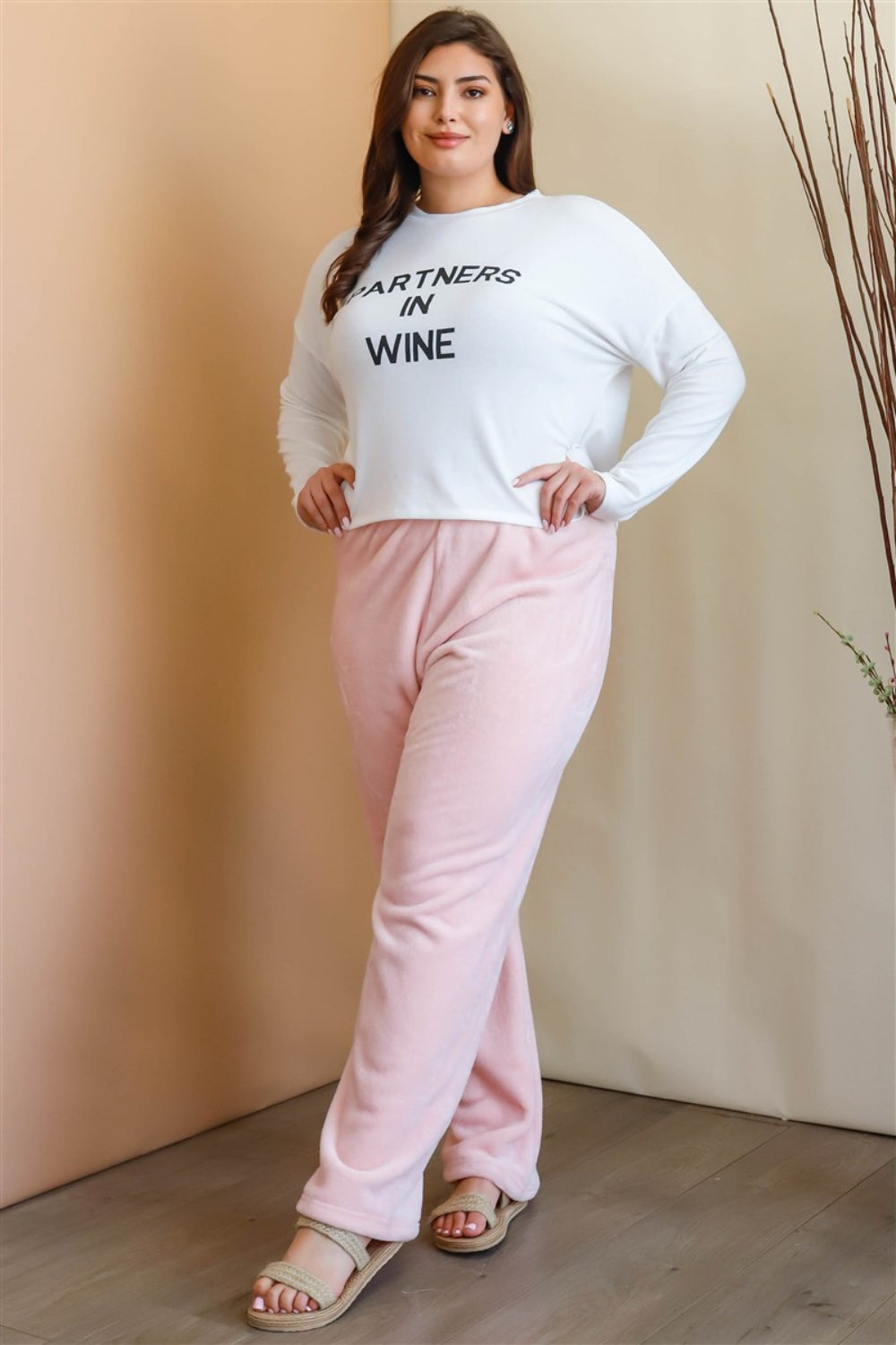 A woman stands in a minimalist room wearing a color-block sweater in beige, white, and light blue, along with Active Usa Plus Size Elastic Waist Wide Leg Pants and beige sandals. She poses with one hand on her hip, embodying a versatile style that combines comfort and elegance.