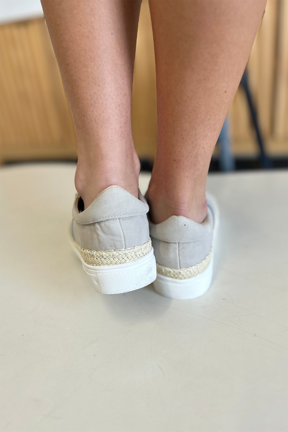 A person wearing the chic CCOCCI Striped Round Neck Sneakers in beige, featuring black and white stripes on a light surface, ideal for everyday wear.