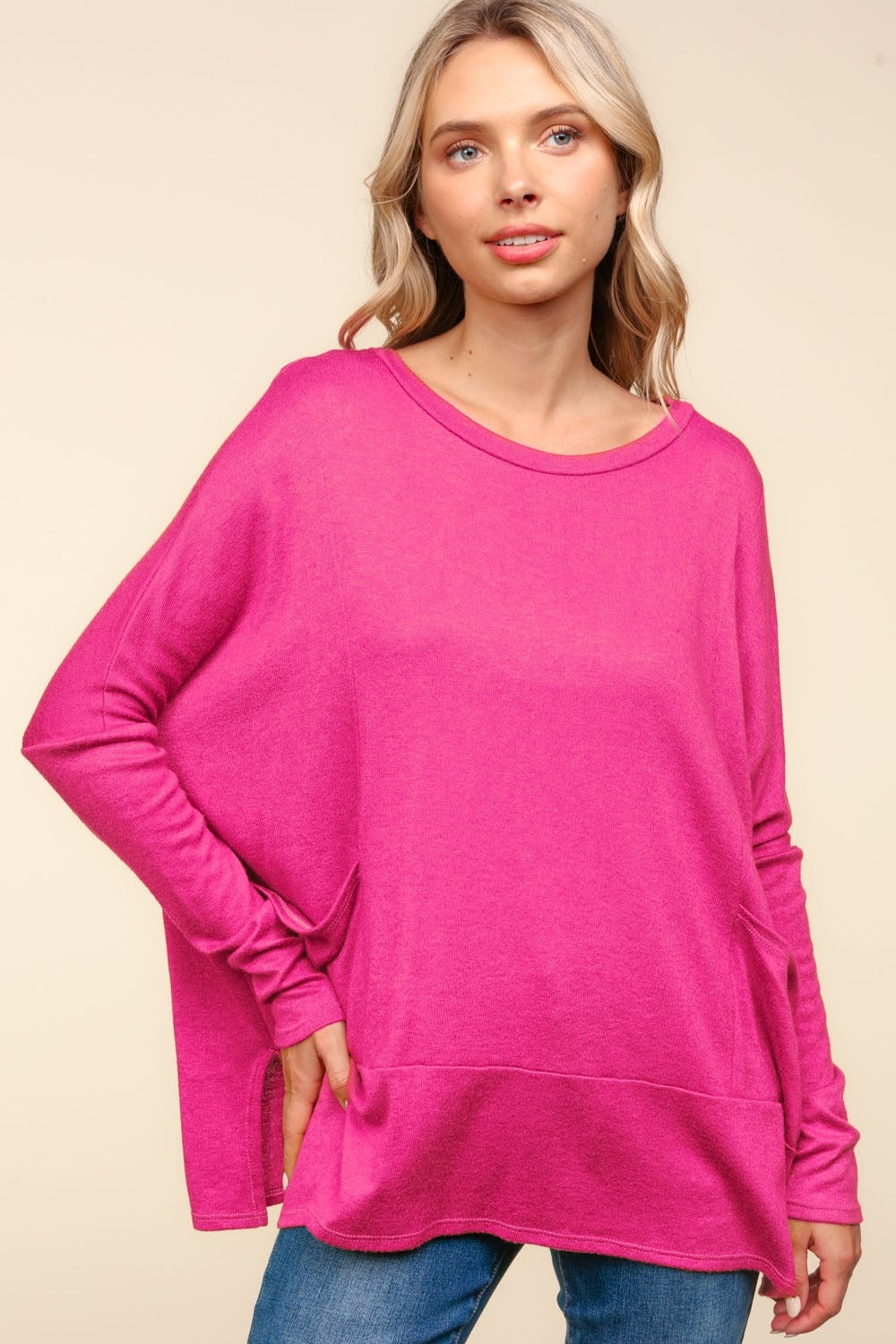 A person wearing a Haptics Dolman Long Sleeve Oversized Knit Top with Pockets in bright pink stands against a plain background.